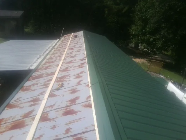 Old rusted panels beside newly installed green metal roofing — Wind Damage Roof Repair by Roofing Brothers in Brighton